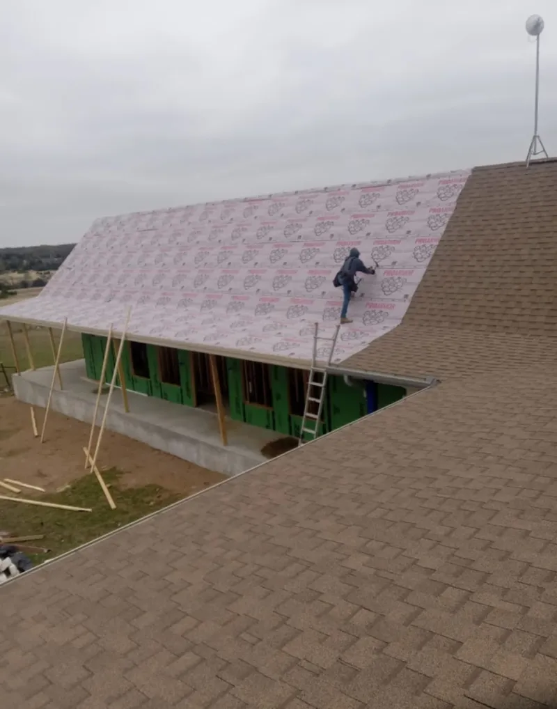 Worker preparing underlayment for a metal roof installation in Rochester